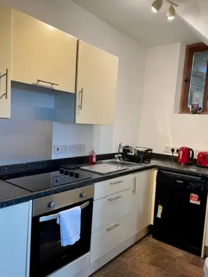 a kitchen with white cabinets and a black stove top oven at The Hay Suite in Aberystwyth