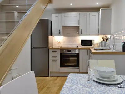 a kitchen with white cabinets and a table with a table cloth at Cornel Clyd Cosy Corner in Cilcennin