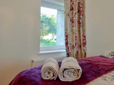 a bed with towels on it with a window at Cornel Clyd Cosy Corner in Cilcennin