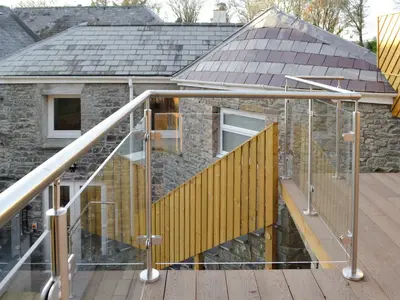 a house with a wooden deck and a metal railing at Cornel Clyd Cosy Corner in Cilcennin