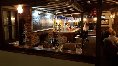 a bar with a fireplace and people sitting at a bar at The Wheatsheaf Inn in Ludlow