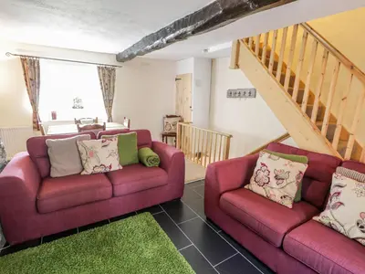 a living room with two red couches and a staircase at Plas Arenig in Blaenau-Ffestiniog