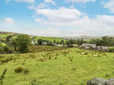a field of grass with sheep in the distance at Plas Arenig in Blaenau-Ffestiniog