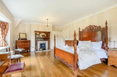 a bedroom with a large bed and a fireplace at Plas Gwynfryn in Llanbedr