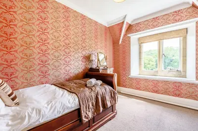 a bedroom with red wallpaper and a bed with a window at Plas Gwynfryn in Llanbedr