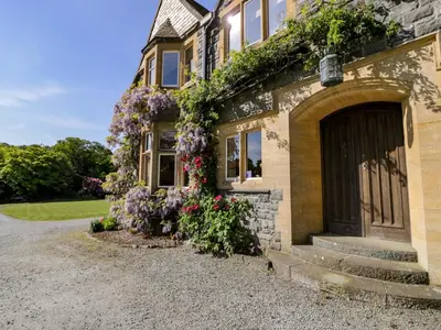 a house with flowers on the side of it at Plas Gwynfryn in Llanbedr