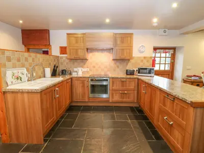 a kitchen with wooden cabinets and a sink at Craig Y Deryn in Tywyn
