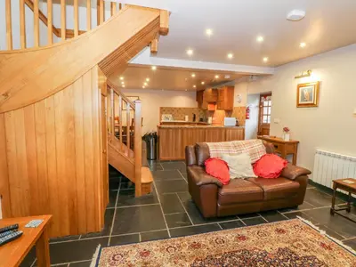a living room with a couch and a staircase at Craig Y Deryn in Tywyn