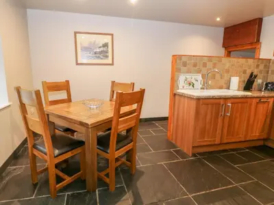 a kitchen with a wooden table and chairs and a sink at Craig Y Deryn in Tywyn
