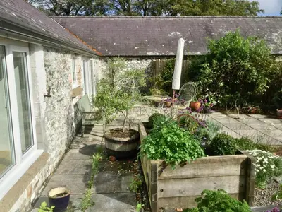 a garden with potted plants and a window at Cuckoo Barn at Penygaer farm near the Brecon Beacons in Llandovery