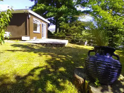 a large blue vase sitting in the grass near a cabin at Sea Moss Cabin in Tywyn