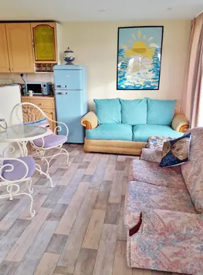 a living room with a blue couch and a table at Sea Moss Cabin in Tywyn