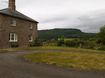 an old brick house with a grass field next to a road at Upper Letton Farm in Leintwardine