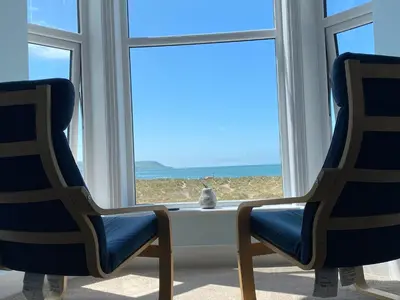 a cat sitting on a window sill looking out at the ocean at Oceandrive in Barmouth