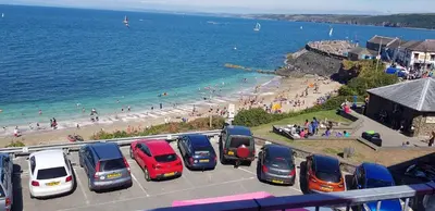 a parking lot with cars parked next to the beach at The Sup Shack Wellington Inn in New Quay