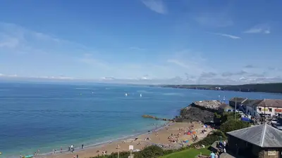 a group of people on a beach near the water at The Sup Shack Wellington Inn in New Quay