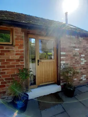a brick house with a wooden door and windows at Little Smithy in Shrewsbury