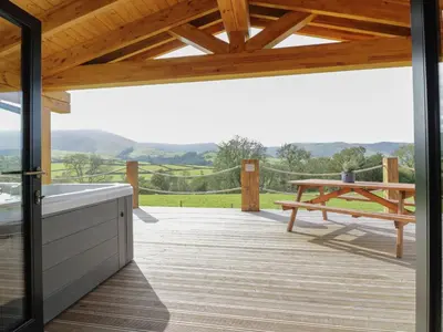 a wooden deck with a picnic table and a bench at Bryn Eiddon Log Cabin in Machynlleth