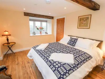 a bedroom with a bed with a blue and white comforter at Stabl, Plas Moelfre Hall Barns in Oswestry