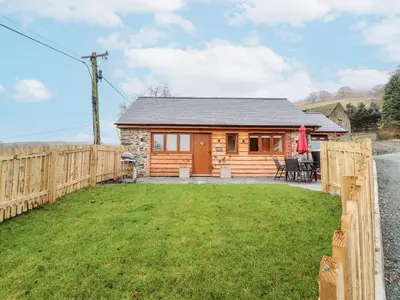 a log cabin with a fence and a yard at Cut Moch, Plas Moelfre Hall Barns in Oswestry