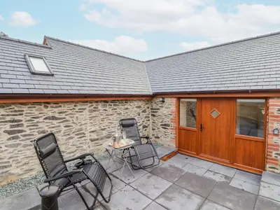 two chairs and a table on a patio at Cut Moch, Plas Moelfre Hall Barns in Oswestry