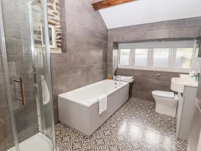 a bathroom with a tub and a toilet and a sink at Cut Moch, Plas Moelfre Hall Barns in Oswestry