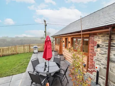 a patio with a table and chairs and a building at Cut Moch, Plas Moelfre Hall Barns in Oswestry