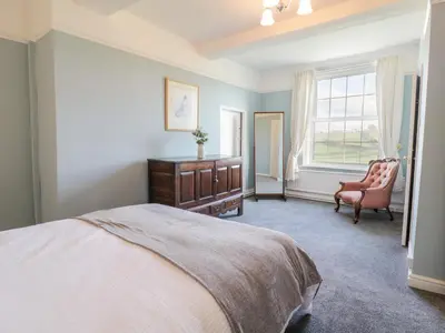 a bedroom with a bed and a chair and a window at Squires Rest in Welshpool