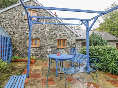 a blue table and chairs in front of a stone house at Felin Iago in Aberystwyth