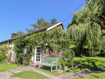 a house with a bench in front of it at Lower Dolgenau- The Cottage in Caersws