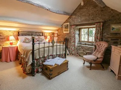 a bedroom with a bed and a chair at Lower Dolgenau- The Cottage in Caersws