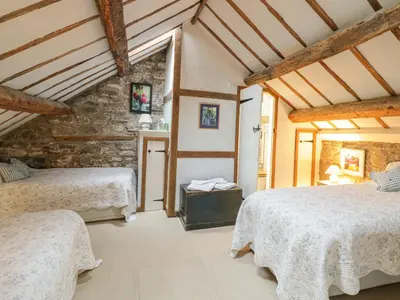 a bedroom with two beds and a stone wall at Lower Dolgenau- The Cottage in Caersws