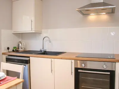 a kitchen with white cabinets and a sink at The Little Dingle in Church Stretton
