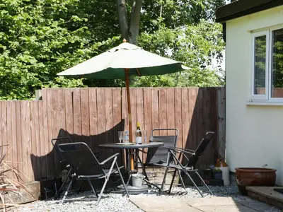 a table and chairs under an umbrella in a backyard at The Little Dingle in Church Stretton