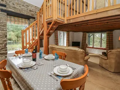 a dining room with a table and chairs and a staircase at Trawsnant Cottage in New Quay