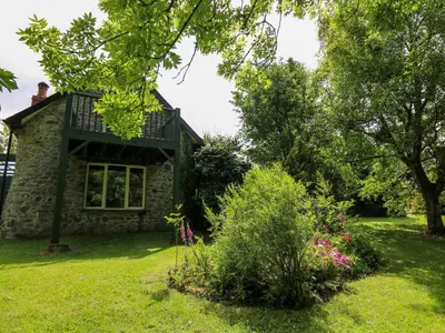 a stone house with a balcony on top of it at Trawsnant Cottage in New Quay