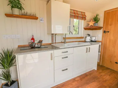 a kitchen with white cabinets and a sink at Marches Way in Rhayader