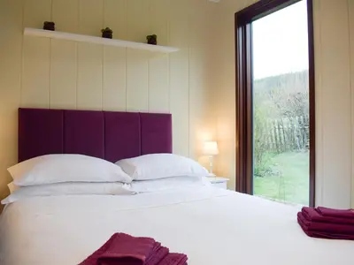 a bedroom with a large white bed with a large window at The Wooden Lodge in Byton
