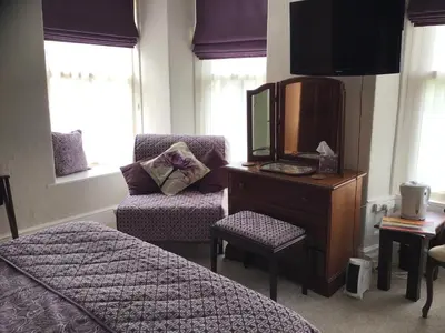 a bedroom with a dresser with a tv and a chair at Beechwood House in New Quay