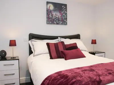 a bedroom with a white bed with red pillows at Alders View Coach House in Craven Arms