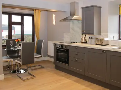 a kitchen with a stove and a table with chairs at Alders View Coach House in Craven Arms