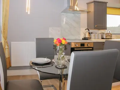 a kitchen with a glass table with a vase of flowers on it at Alders View Coach House in Craven Arms
