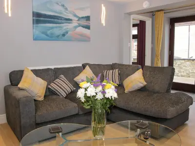 a living room with a couch and a vase of flowers at Alders View Coach House in Craven Arms