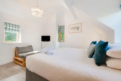 a bedroom with a large white bed and a chair at 2 Bed in Aberdyfi oc-wah694 in Aberdyfi
