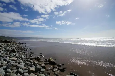 a beach with a lot of rocks and the ocean at 2 Bed in Barmouth oc-wah698 in Talybont