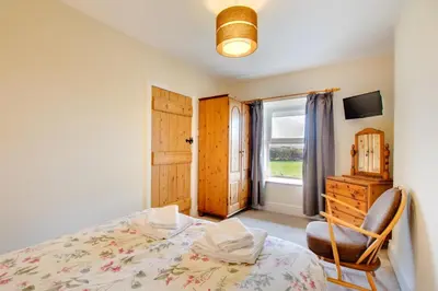 a bedroom with a bed and a chair and a window at 2 Bed in Barmouth oc-wah698 in Talybont
