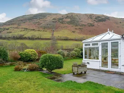 a small greenhouse in a garden with a hill in the background at Hoot House in Abergynolwyn