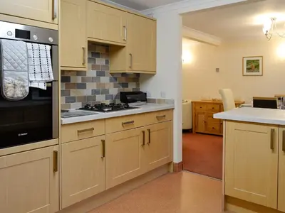 a kitchen with wooden cabinets and a stove top oven at Hoot House in Abergynolwyn