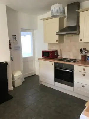 a kitchen with white cabinets and a black stove top oven at Aelfor Cozy Cottage in Barmouth