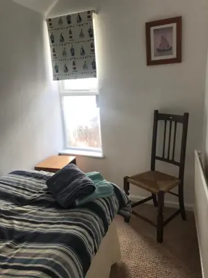 a bedroom with a bed and a chair and a window at Aelfor Cozy Cottage in Barmouth
